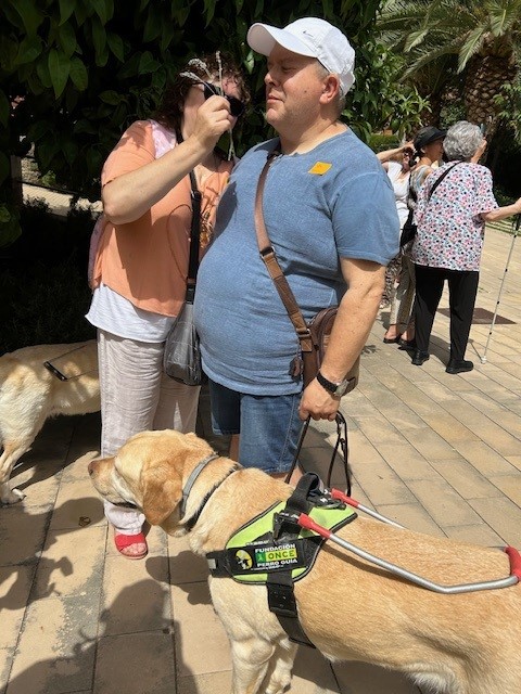 Dues persones amb sordceguesa oloren una planta del jardí.