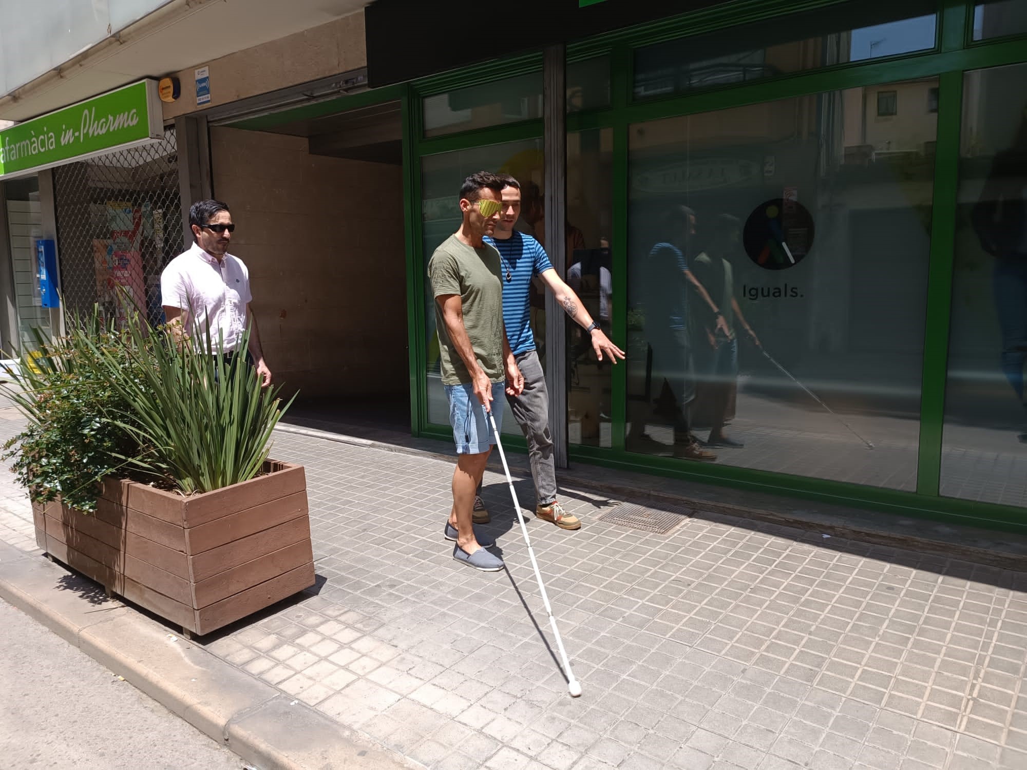 Xavi Marina caminant amb el bastó blanc i antifaç pel carrer