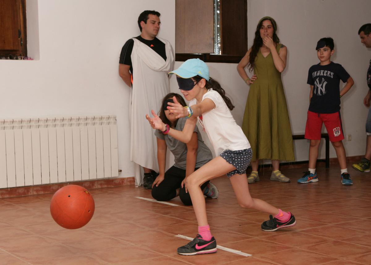 Una nena prova amb el llençament d'una pilota amb picarols com jugar al goalball.