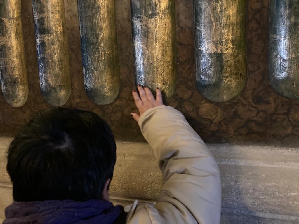Imatge d'un dels assistents a la visita guiada accessible tocant una pared de la Catedral de vIC