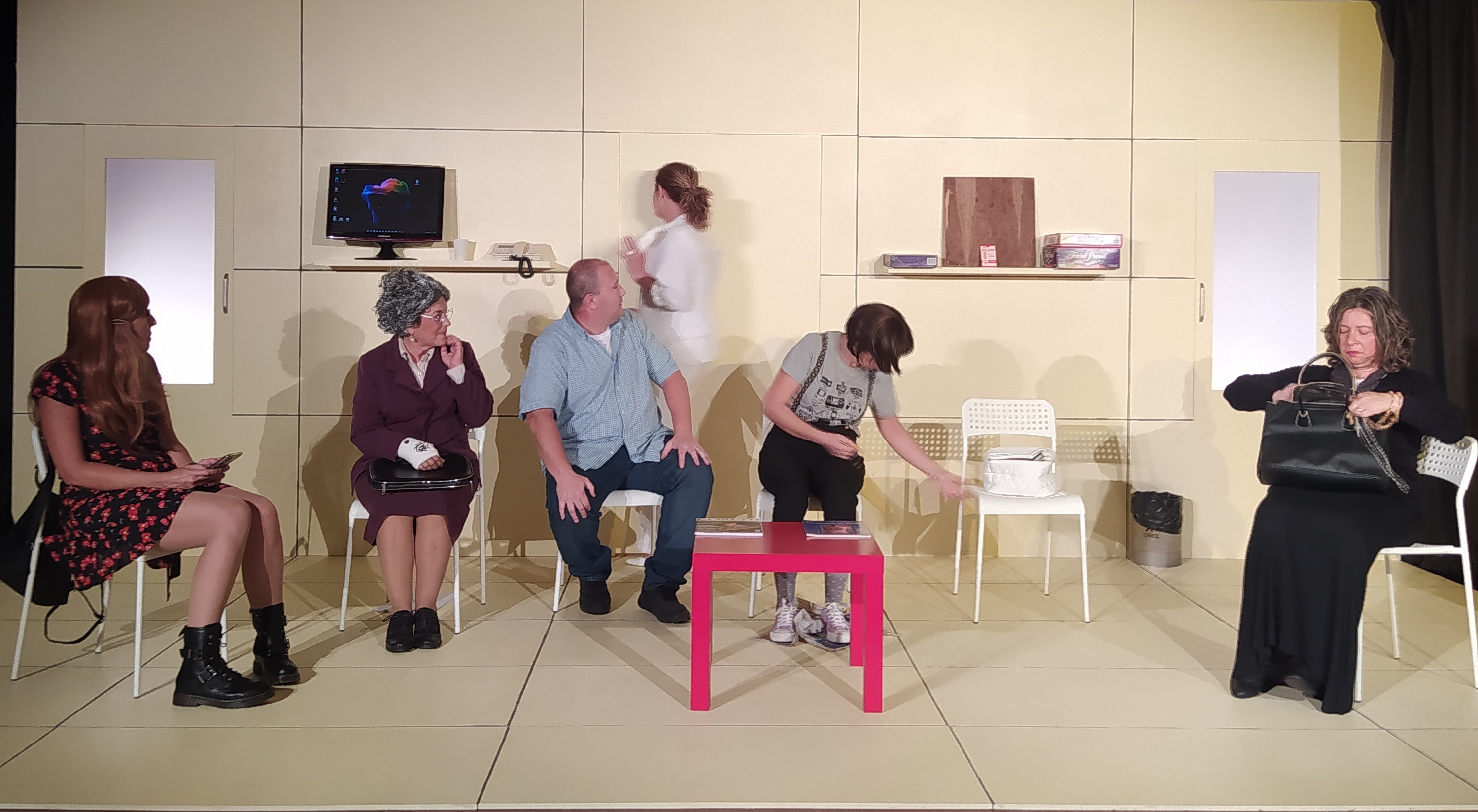 Imatge on apareixen els actors en un decorat que simula una sala d'espera d'una consulta mèdica