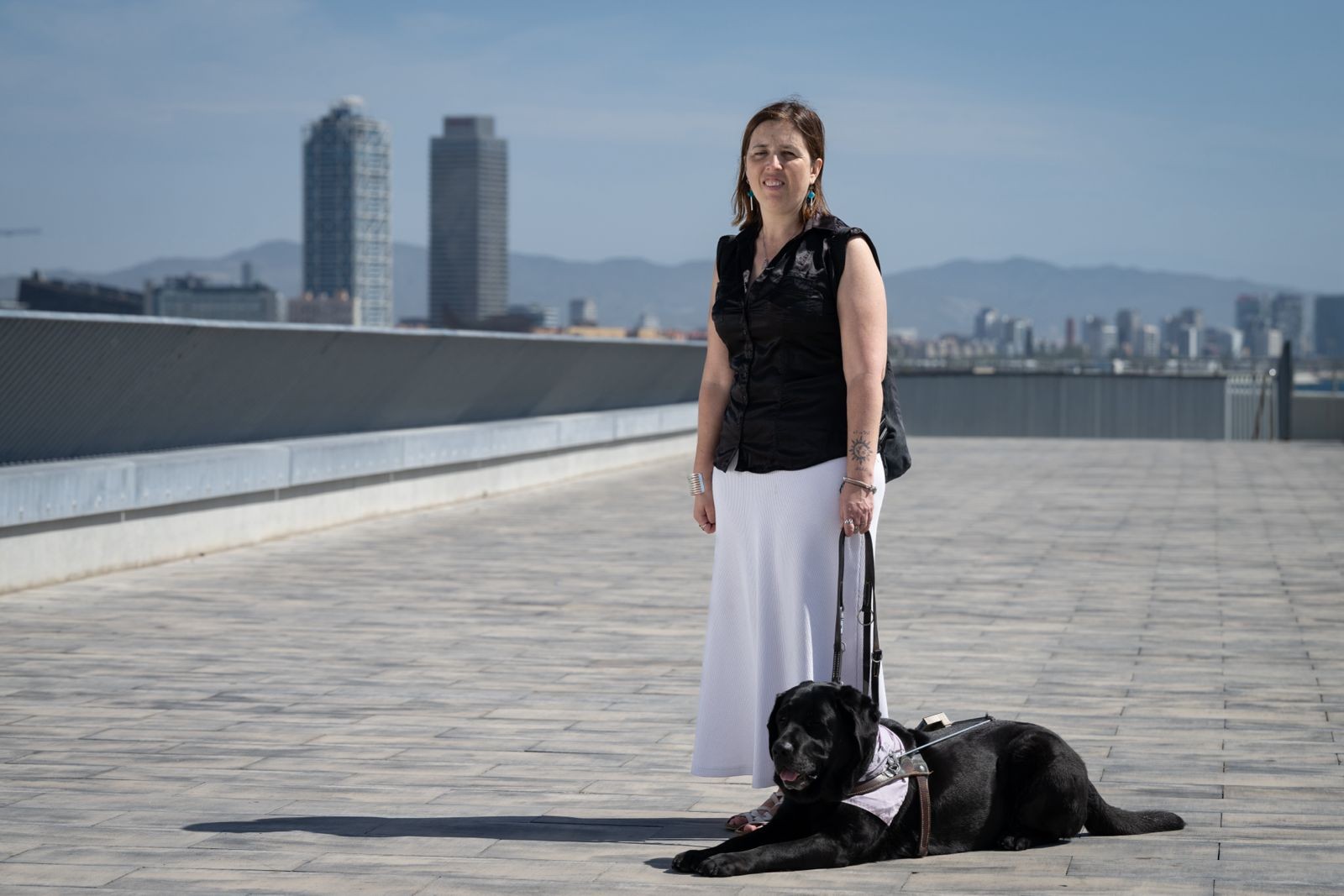 Imatge d'arxiu, amb Anaïs Garcia, persona cega amb el seu gos pigall, amb les Torre Mapfre al fons.
