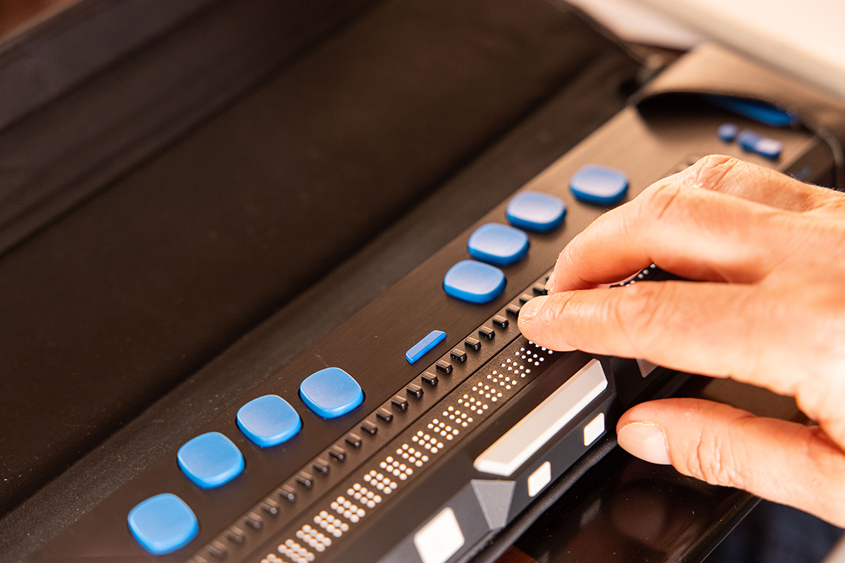 Detall d'una mà utilitzant una línia braille.