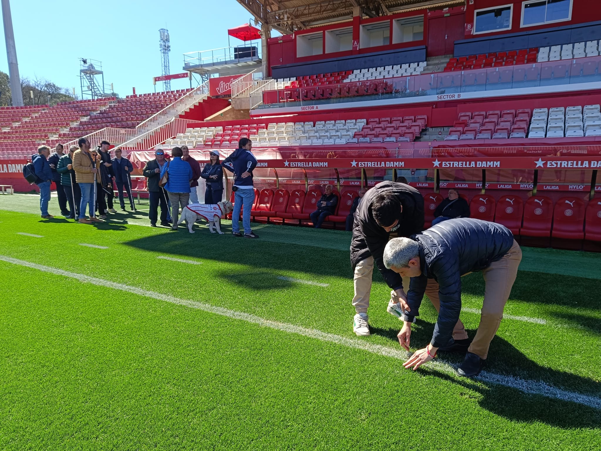 Un grup de persones cegues toca la gespa de Montilivi.
