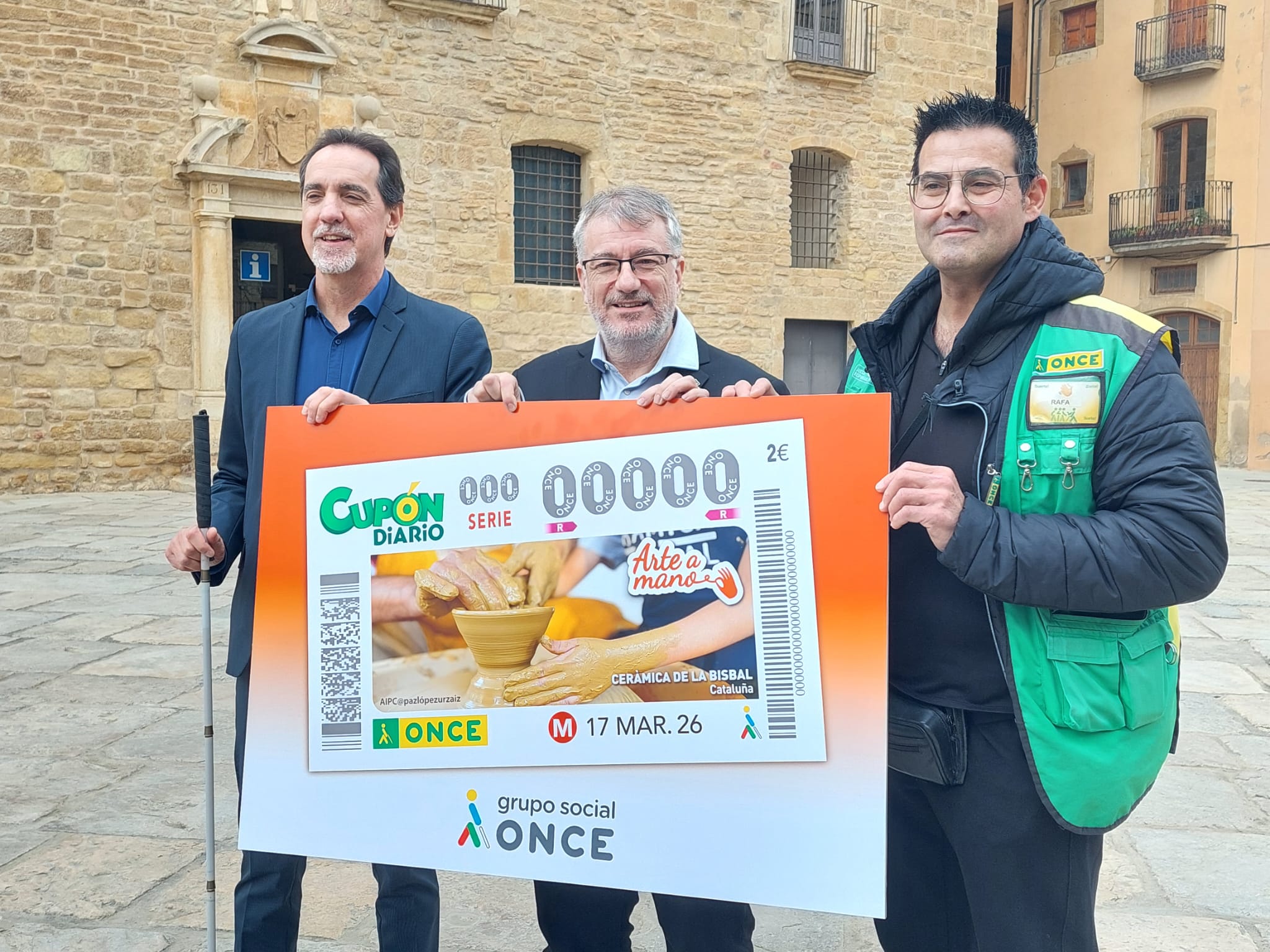 Enric Botí, delegat de l’ONCE a Catalunya, &nbsp;lliurà&nbsp; a Òscar Aparicio, alcalde de la Bisbal, una il·lustració emmarcada d’aquest cupó. També es el va acompanyar el venedor de productes de loteria social, responsable i segura de l'ONCE, Rafa Montero.