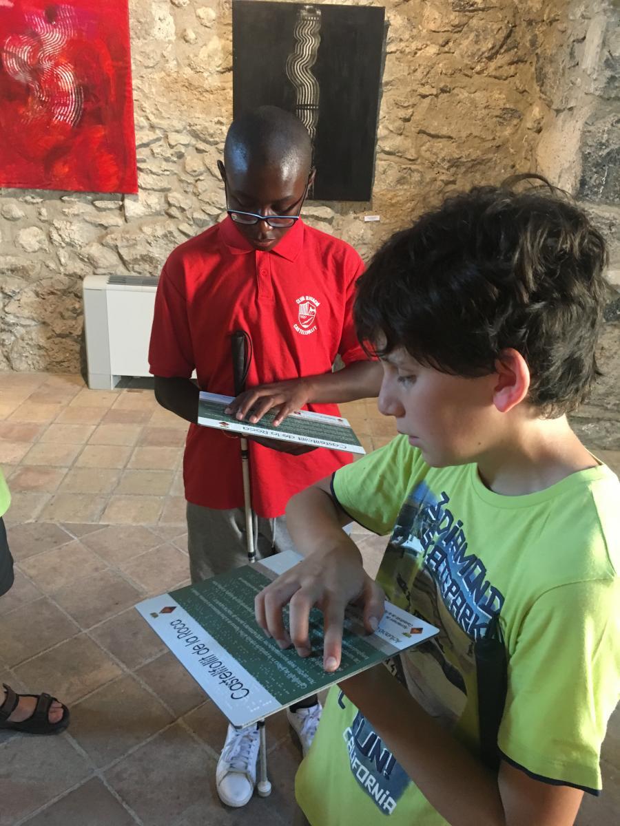 Dos nens afiliats llegeeixen una informació en Braille.