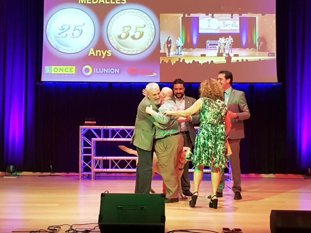 Juan de Dios, medallista de 35 anys, a l'escenari, abraçat pel delegat,  Xavier Grau i amb Enric Botí.