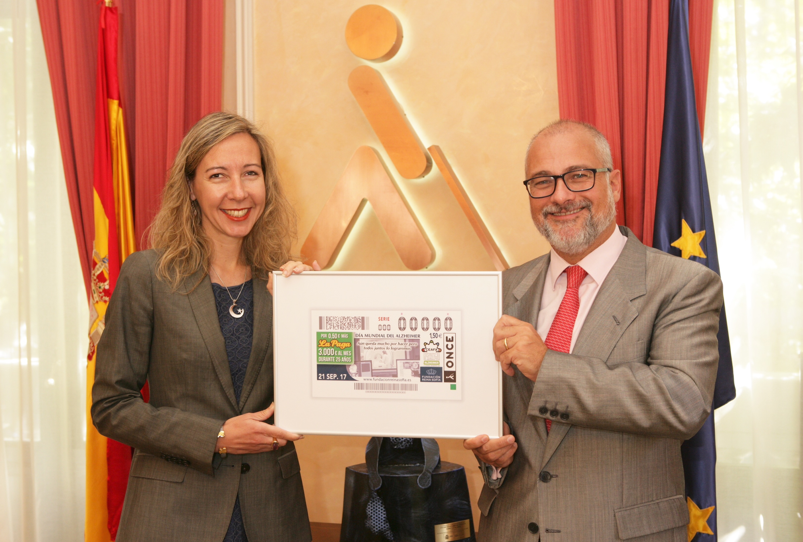 patricia_sanz_vicepresidenta_de_la_once_entrega_a_jose_luis_nogueira_secretario_de_la_fundacion_reina_sofia_una_lamina_enmarcada_del_cupon_del_dia_del_alzheimer.jpg