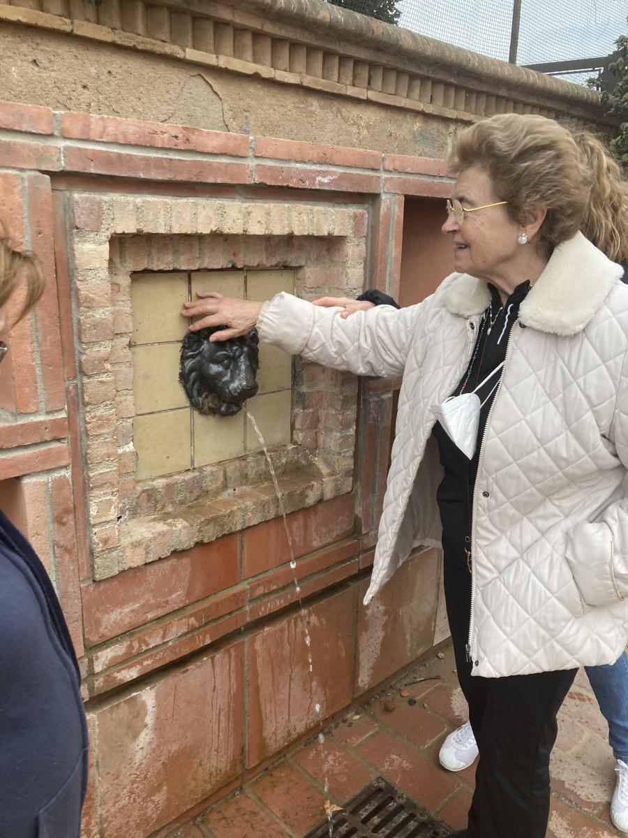 Una dona toca la font del lleó del passeig.