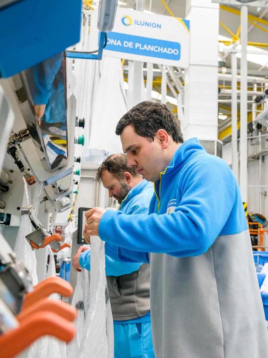 Dos treballadors treballen en Una Bugaderia d'Ilunion.