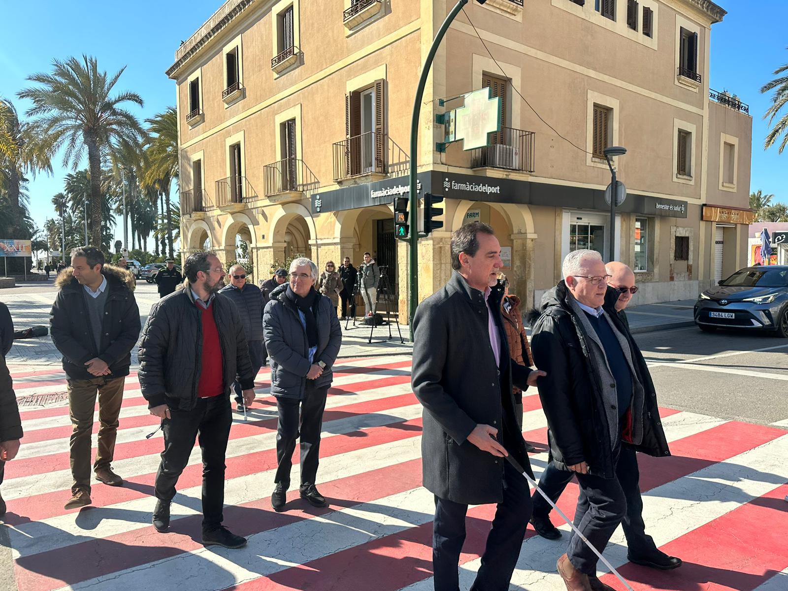 Imatge dels assistents a la presentació dels 62 semàfors creuant per un pas de zebre on s'ha instal·lat un d'aquests dispositius sonors