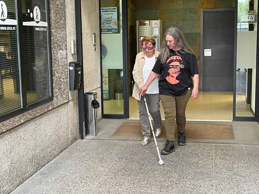 Mercè Batlle caminant amb bastó blanc i antifaç