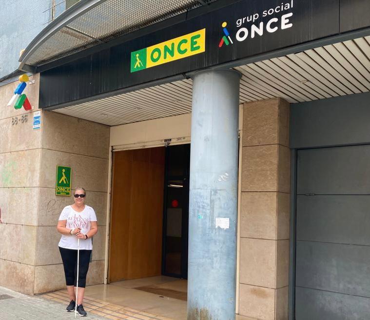 Entrada de l'Agència de l'ONCE a Badalona on es veu una dona amb un bastó blanc davant la porta