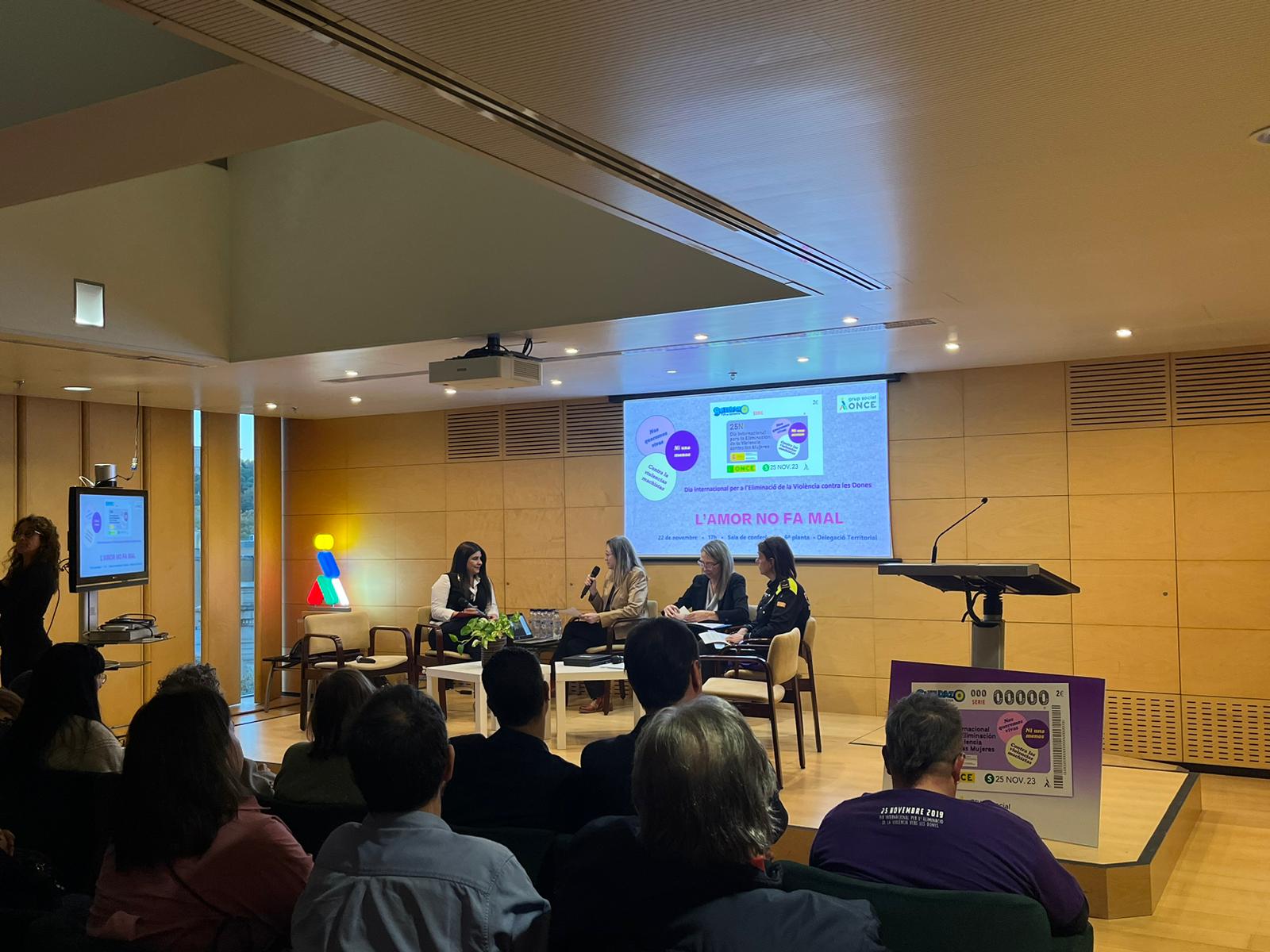 Elizabeth García, tècnica Compass d’Inserta Fundació ONCE. ‘Mujeres en Modo ON-VG’; Pamela Palenciano, actriu, autora, comunicadora i activista feminista (via zoom); i Cèlia Bertomeu, caporal de la Policia Local de La Garriga. Amb María de la Sierra López, vicepresidenta 2a del Consell Territorial de l'ONCE a Catalunya i M. Dolors Guiu, agent d’Igualtat de l’ONCE a Catalunya, en una sala plena de gom a gom.
