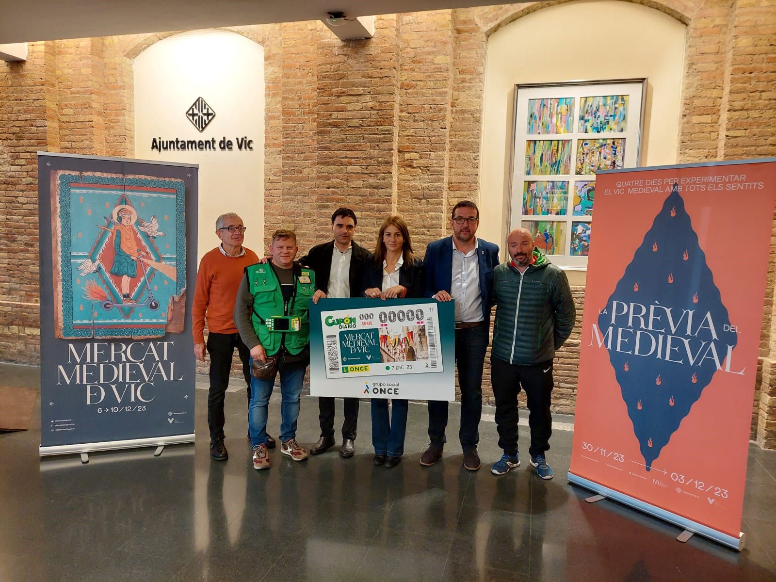 Foto de família de la gent ONCE de Vic amb l'alcalde de Vic, Albert Castells i Bet Piella, regidora de Fires i Mercats i Xavier Omella, director de l'Agència de l'ONCE a Vic, al centre.