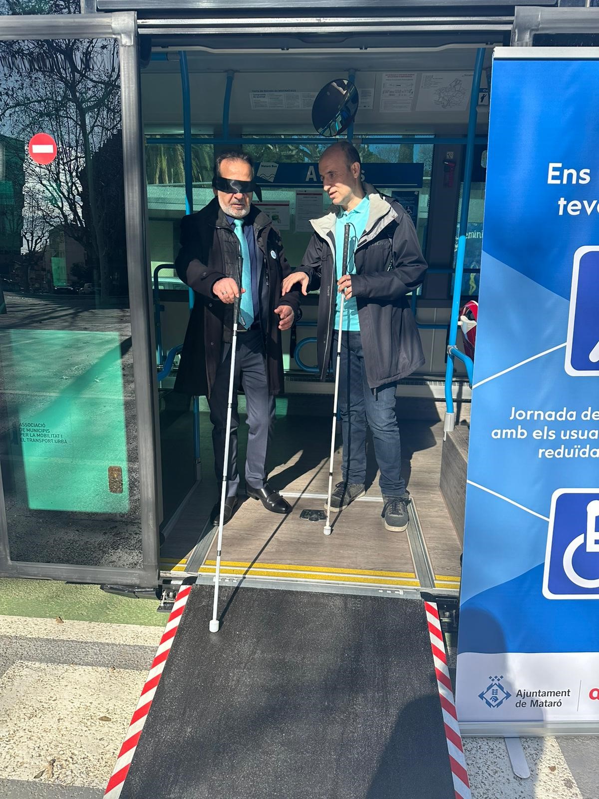 Cesc Avellaneda, gerent d'Operacions de la Xarxa de Transports Urbans de Mataró. I , des de l'agència de l'ONCE a Mataró, un grup d'afiliats i afiliades, un d'ells l'acompanya amb bastó blanc.