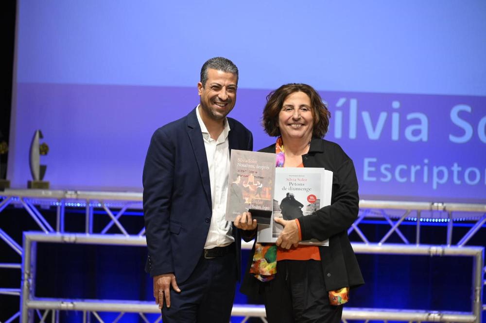 L’escriptora Sílvia Soler rep de mans de David Bernardo, president del Consell Territorial d'ONCE Catalunya, com a record, un exemplar en braille del seu llibre 'Petons de diumenge' i un altre en sonor de 'Nosaltres, després'.