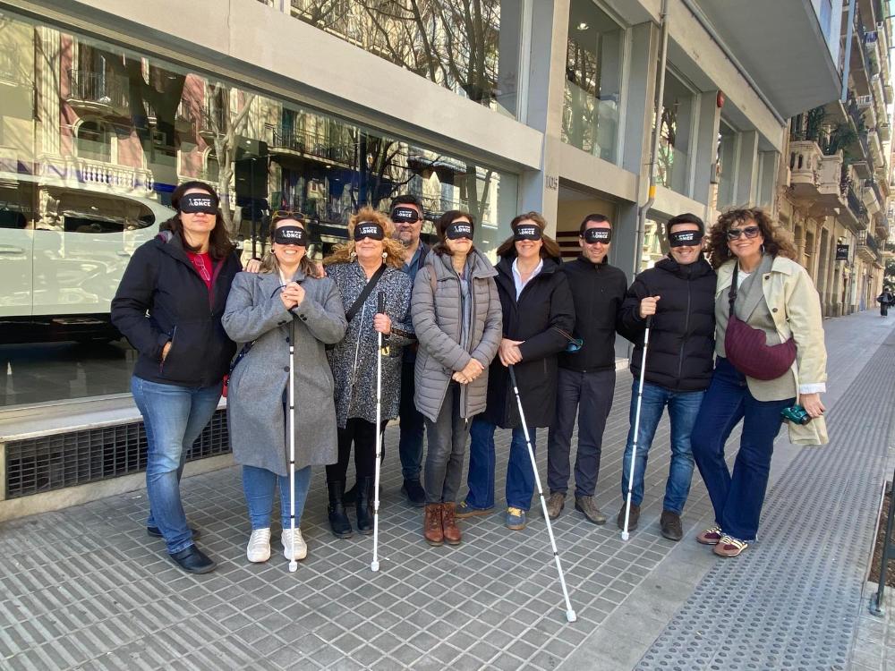 Assistents a la presentació de la guia fent la pràctica amb bastó blanc i antifaç pel carrer