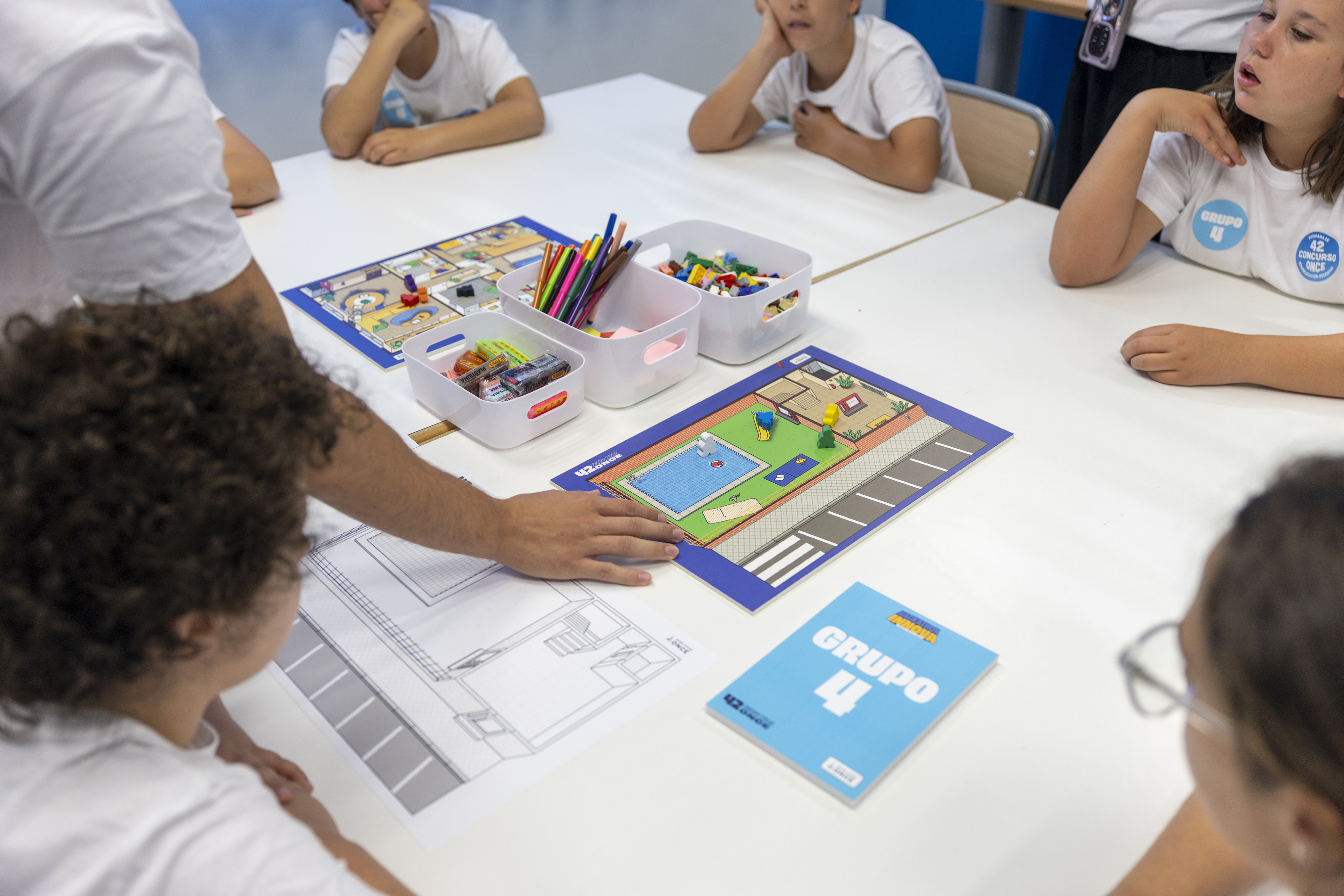 Estudiants treballen plegats al voltant d'una taula de classe.