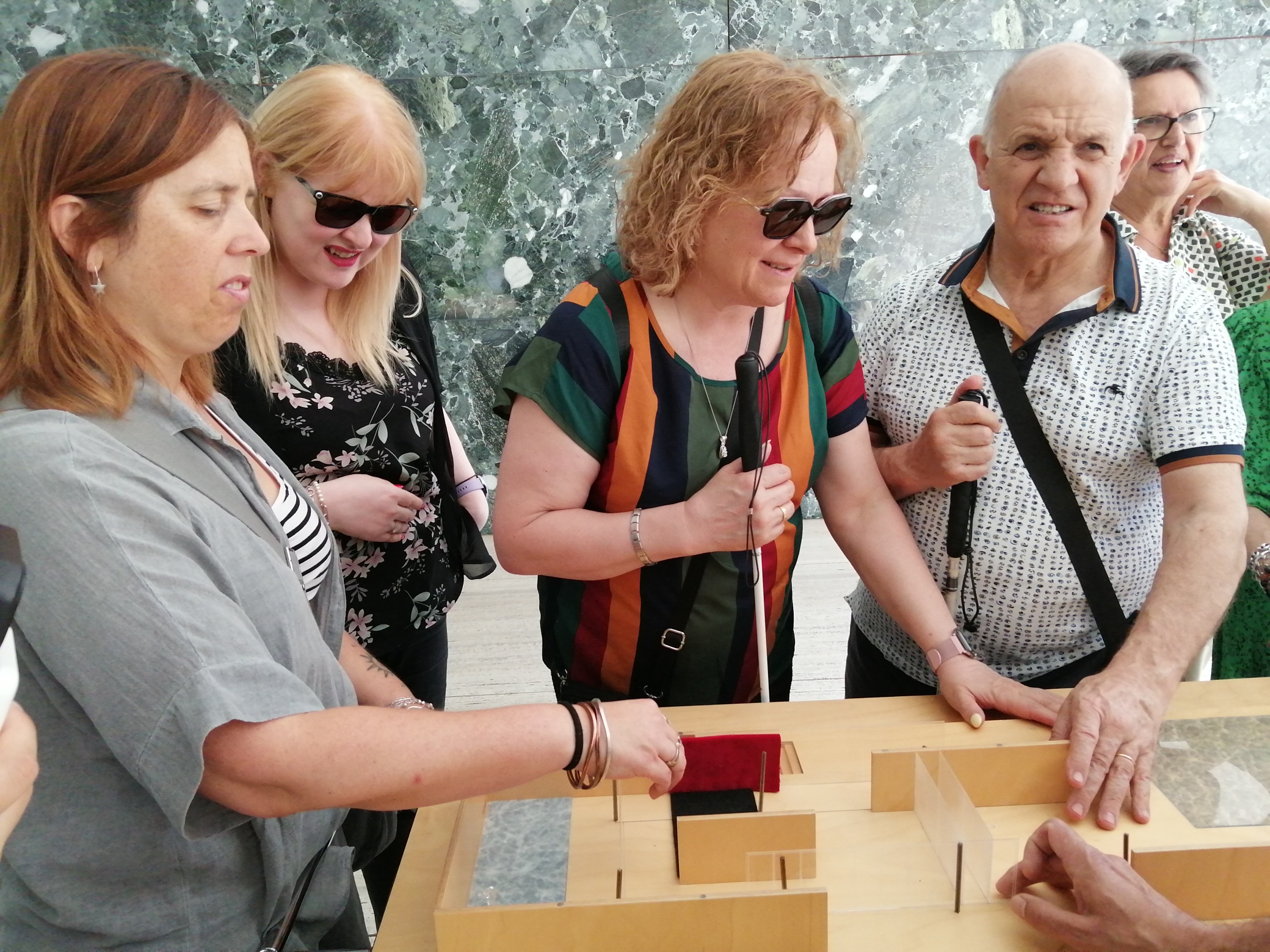 Grup de persones cegues tocant la maqueta tàctil del Pavelló Mies van der Rohe.